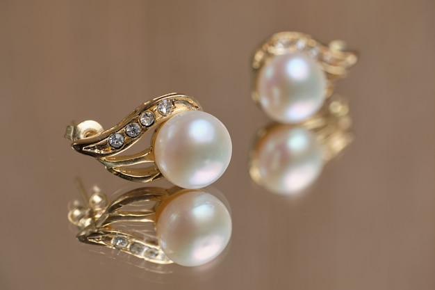 Pearl earrings on a glass table.