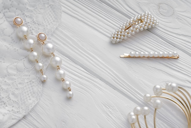 Pearl golden Earrings, hairpins and bracelet on white wood