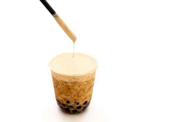 Pearl milk iced tea with cream on top isolated in clipping path.