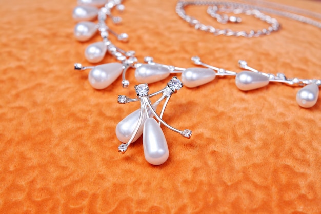 Pearl necklace and earrings. A beautiful wedding decoration on an orange background. Bride accessories