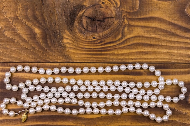 木製の背景に真珠のネックレス上面図コピースペース
