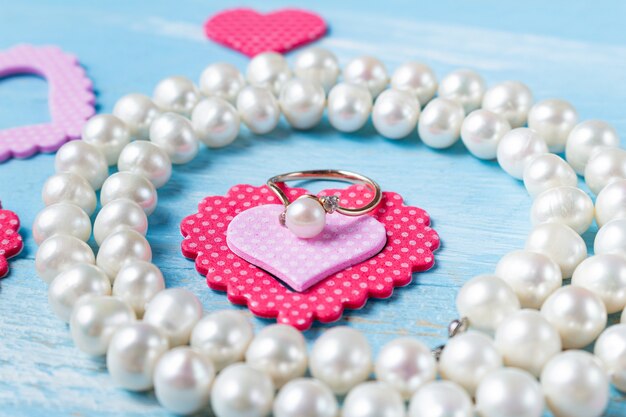 Pearl ring, necklace and heart on blue