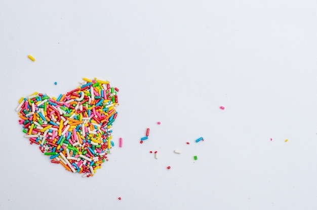 Pearls sprinkles and dragees for decoration of heartshaped cake on white background