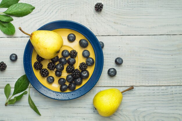 Pears and blueberries in a plate on a white wooden table