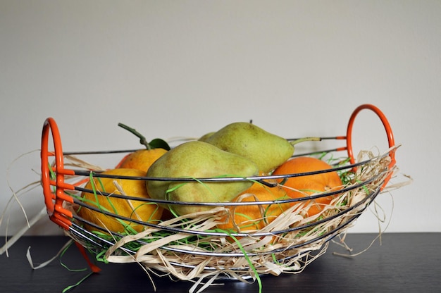 Pears and oranges in basket on table