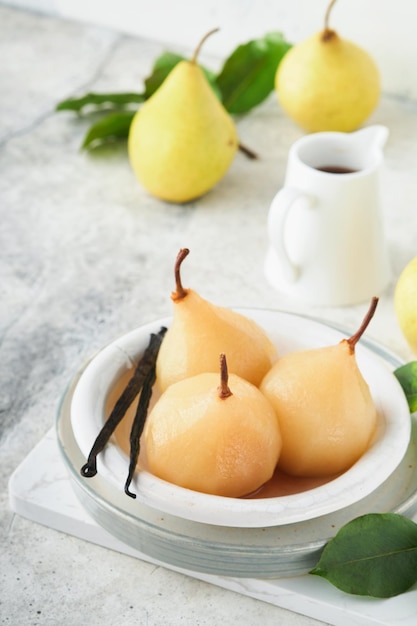 Pears Poached pears in syrup Traditional dessert sliced server in a white plate with leaves and at home on a light background Delicious dessert for holiday