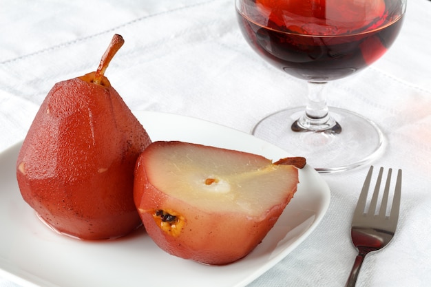 Pears poached in red wine in a white bowl