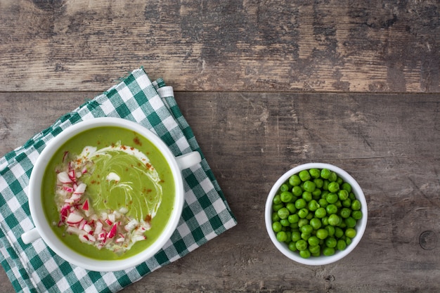 Peas cream with radishes on rustic wooden table top view