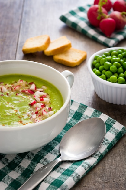 Peas cream with radishes on rustic wooden table