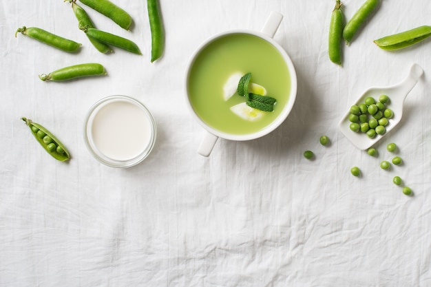 Peas soup in bowl with pea bods and cream