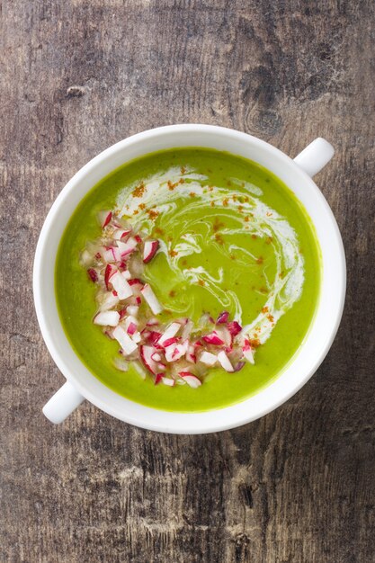 Peas soup with radishes on rustic wood top view