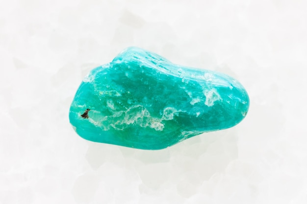 Pebble of amazonite gemstone on white marble