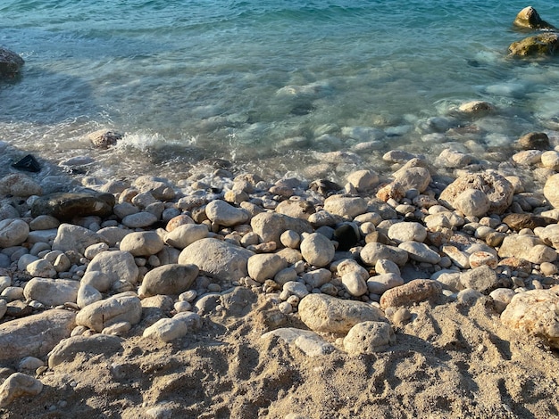 Pebble stones on the shore close up in the blurry sunset light in the distance background