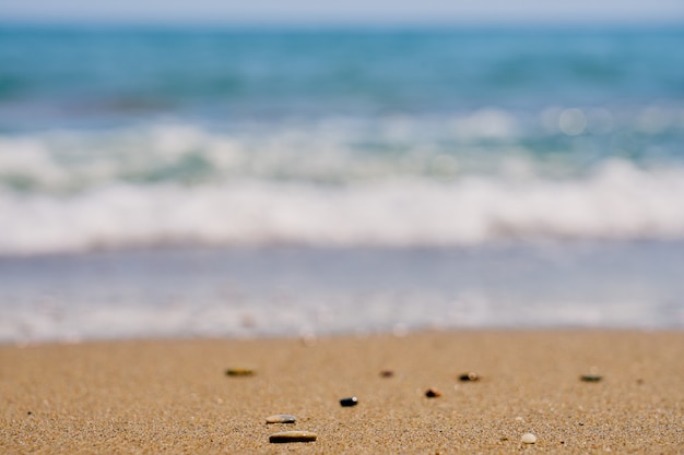 Pebble on tropical beach with blurred waves on the background.