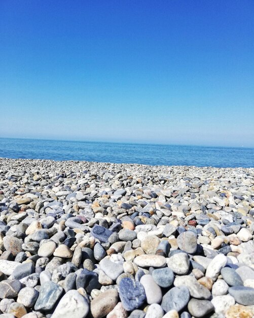 Pebbles on beach against clear blue sky