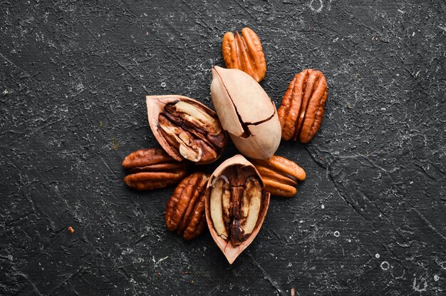 Pecan nut on black stone background Assortment of pecans Top preview Free space for your text