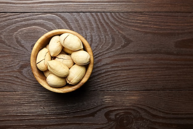 Pecan nuts in bowl on brown wooden table top view