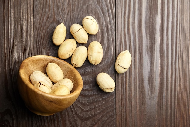 Pecan nuts in bowl on brown wooden table top view