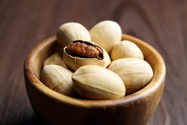 Pecan nuts in bowl on brown wooden table