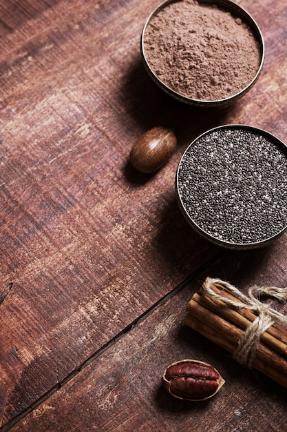 Pecan nuts, chia seeds and cocoa in a bowls on a wooden table