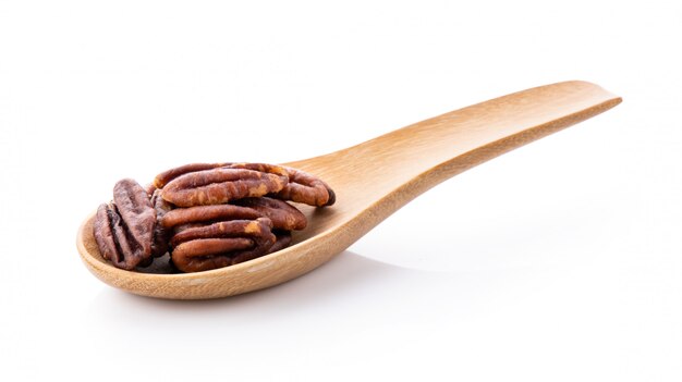 Pecan nuts topped with light salt in wood spoon on white