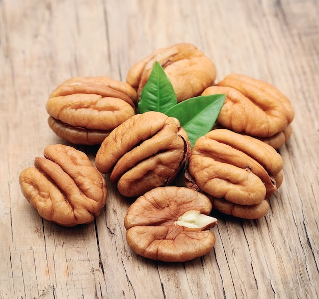 Pecan nuts with leaves close up on wooden table