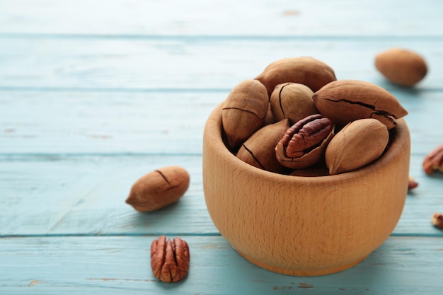 Pecan nuts on wooden bowl on blue wooden background