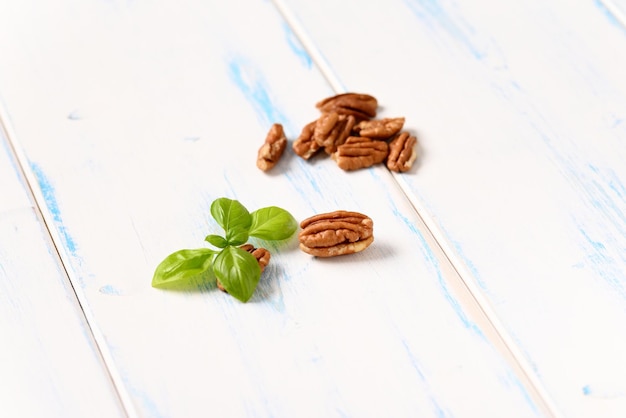 Pecannoten met basilicumblad op een licht houten tafel