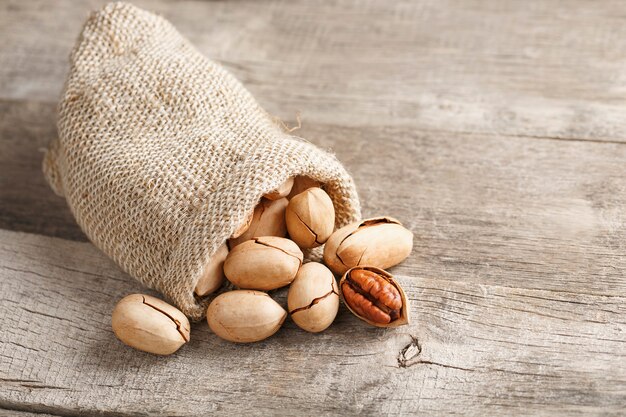 Pecans spill out of a sackcloth on a wooden table