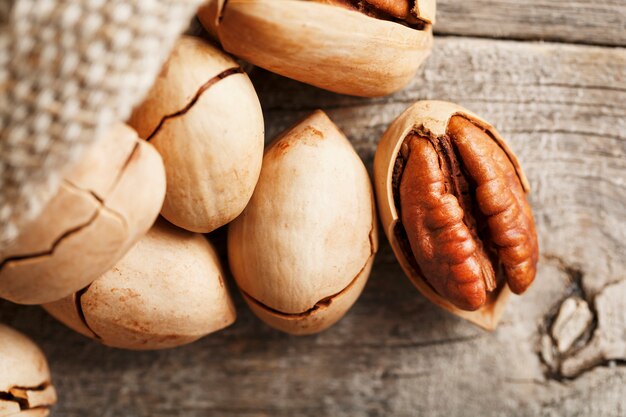 Pecans spill out of a sackcloth on a wooden table