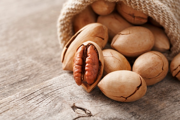 Pecans spill out of a sackcloth on a wooden table