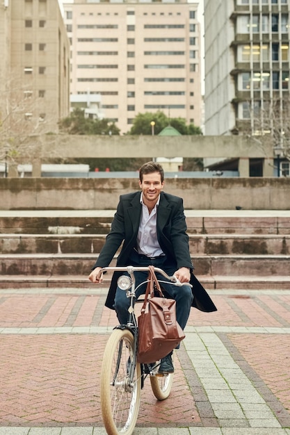Педалирование по городу больших возможностей Портрет молодого бизнесмена, едущего на работу на велосипеде