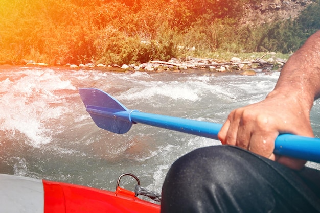 Peddel in de hand op de rand van een vlot raftend op een bergrivier