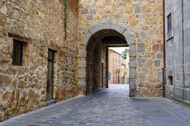 Pedestrian alley in medieval town with stone arch under old\
building. ãvila, spain.