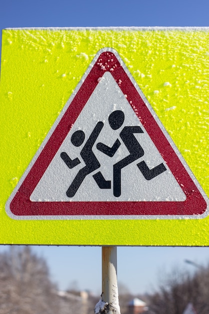 Pedestrian crossing sign on a yellow background. On a Sunny winter day.