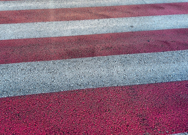 Pedestrian crossing stripes of white and red color on asphalt