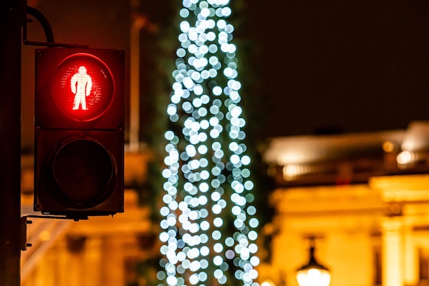 Photo pedestrian semaphore with red light and defocused christmas tree lights in the background