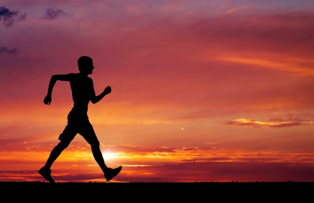 Pedestrianism. Silhouette of sportsman. Silhouette of running on sunset fiery background.