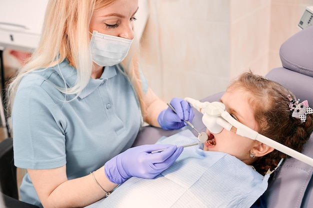 Pediatric dentist examining child teeth with dental explorer and mirror