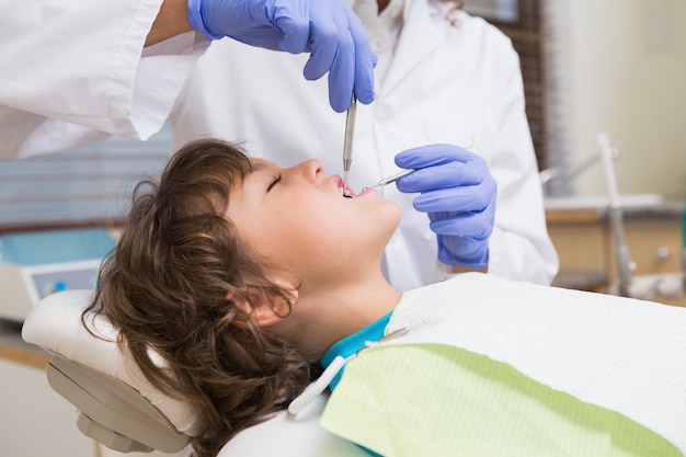 pediatric dentist examining a little boys teeth in the dentists chair