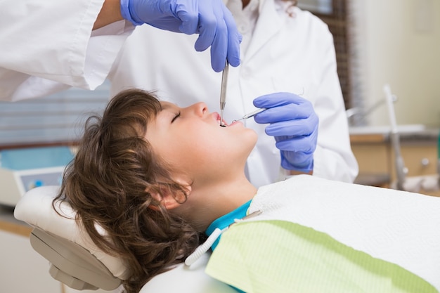 Pediatric dentist examining a little boys teeth in the dentists chair