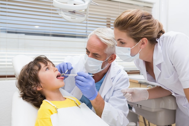 彼の助手と少年の歯を調べる小児歯科医