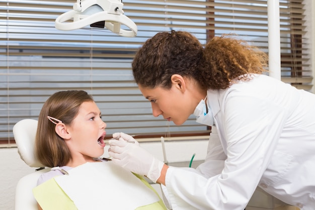 pediatric dentist examining little girls teeth in the dentists chair
