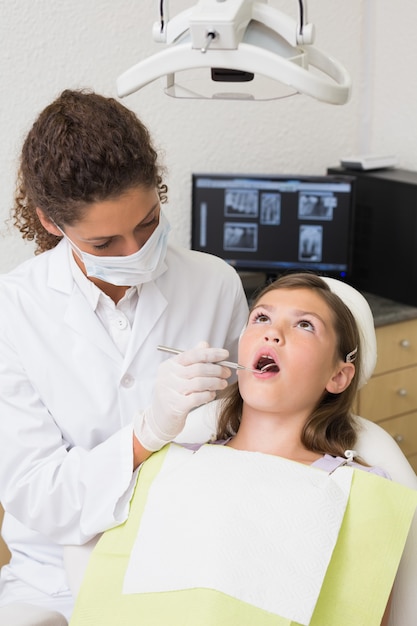 歯科医の椅子の患者の歯を検査する小児歯科医