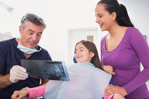 Pediatric dentist explaining to young patient and her mother the x-ray