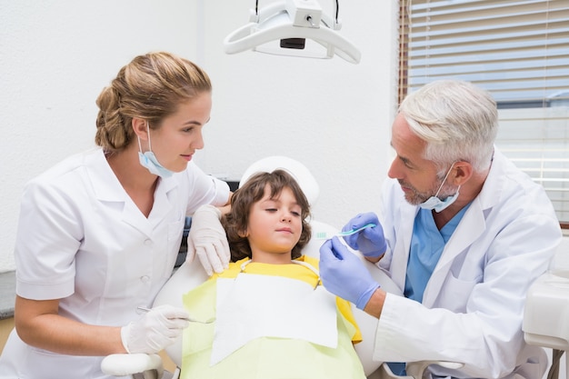 Pediatric dentist showing little boy how to brush his teeth