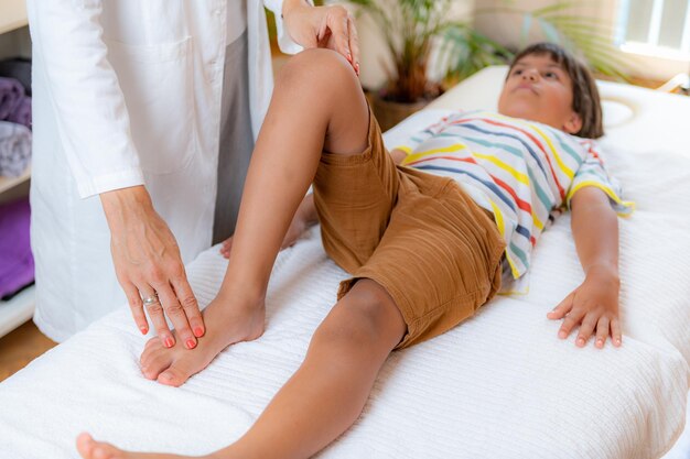 Photo pediatric doctor doing medical exam with boy on bed