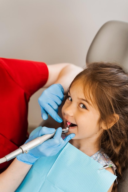 Pediatric girl dentist makes professional teeth cleaning in dentistry Professional hygiene for teeth of child in dentistry Pediatric dentist examines and consults kid patient in dentistry