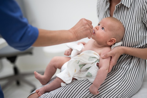 Photo pediatrician administring oral vaccination against rotavirus infection to little baby in presence of