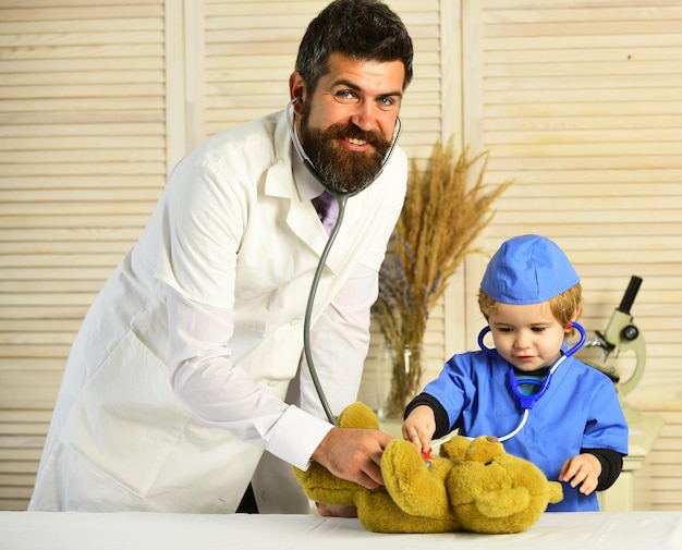 Pediatrician and assistant examines teddy bear Father and kid